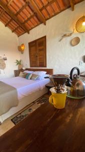 a bedroom with a bed and a table with a pot at Preá Chalé Tsuru in Cruz
