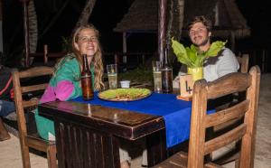 a man and woman sitting at a table with a plate of food at le Repaire des Pirates in Sainte Marie