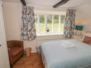 a bedroom with a bed and a chair and windows at Hillside Cottage in Monmouth
