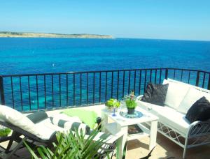 a white couch sitting on a balcony with the ocean at Seafront apartment Terrace, lounger & Panoramic ocean views in Mellieħa