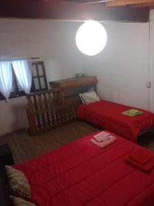 2 Betten in einem Zimmer mit roter Bettwäsche in der Unterkunft Alojamiento por día Merlo San Luis in Merlo