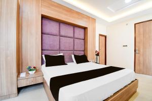 a bedroom with a large bed with a purple headboard at Hotel O Drishti Grand in Lucknow +40 photos
