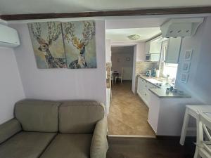 a living room with a couch and a kitchen at Levendula Kuckó - PatakLak Vendégház in Orfű