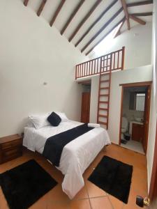 1 dormitorio con 1 cama con sábanas blancas y almohadas negras en LeyvaYork Apartasuites, en Villa de Leyva 14 fotos más