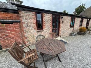 ein Holztisch und zwei Stühle auf einer Terrasse in der Unterkunft lovely Apple Cottage A peach in Bridport