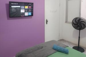 a room with a tv on the wall and a chair at Studio 1033 Niterói Centro in Niterói