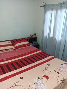 a bedroom with a bed with a red and white blanket at Familia Cabrera Rojas in Nueva Alborada