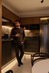 ein Mann steht in einer Küche und hält ein Glas in der Unterkunft Flat ESPETACULAR PRAIA DE CAMBURI Long Stay in Vitória + 57 Fotos