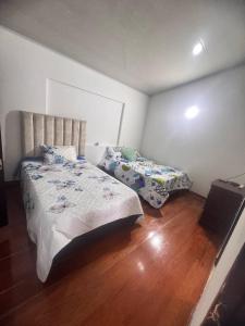 a bedroom with two beds and a wooden floor at La Camelia in Estación El Salto