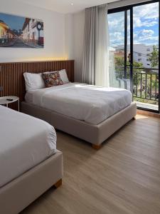 two beds in a hotel room with a balcony at Villa Milá in Salento