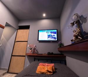 Un dormitorio con una cama y un televisor en la pared. en habitación para 1, en Iquitos