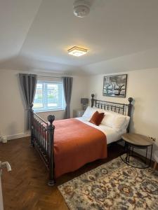 a bedroom with a bed with an orange bedspread at Siennas Modern 1 bed room apartment with ensuite in Kidlington