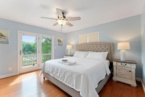ein Schlafzimmer mit einem weißen Bett und einem Deckenventilator in der Unterkunft Shades of Summer by AvantStay Gazebo Dock View in Cornelius