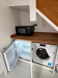 a kitchen with a microwave and a washing machine at Siennas Modern 1 bed room apartment with ensuite in Kidlington