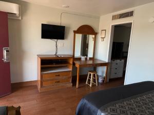a bedroom with a desk and a dresser with a mirror at Apple Valley Motel in Apple Valley