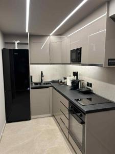 a kitchen with a black refrigerator and white cabinets at ANAVASI Loft SUITE in Alexandroupoli