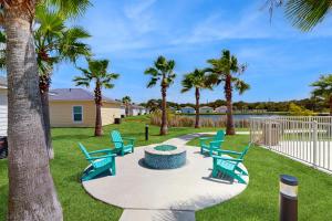 een patio met blauwe stoelen en palmbomen bij Seaglass Cottage in Rockport