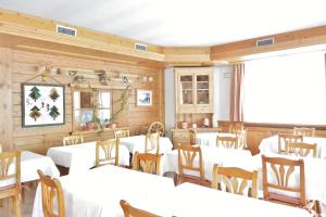 un comedor con mesas blancas y sillas de madera en Hotel Garnì al Plan, en Livigno