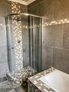 a shower stall with a tub in a bathroom at 17 Zurich Drive House in Margate