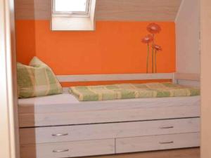 a bed in a room with an orange wall at Ferienhaus Steinger am Blumengässle in Müllheim