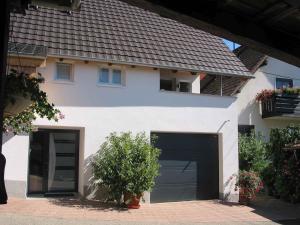 une maison blanche avec deux portes de garage devant elle dans l'établissement Ferienhaus Steinger am Blumengässle, à Müllheim