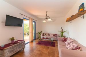 a living room with a couch and a flat screen tv at Villa Alcumissu in Calangianus