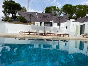 a pool with chairs and umbrellas in front of a house at Finca Celia Competa in Cómpeta