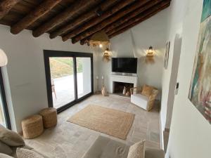 a living room with a fireplace and a large window at Finca Celia Competa in Cómpeta