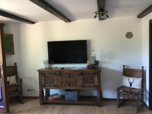 a television on a wooden stand in a room with two chairs at Haus am Waldrand in Todtmoos