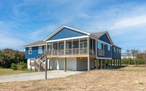 a blue house with a deck on a beach at Laughing Place - Southern Shores, 175 Ft to Beach, Pool Table, Pets OK, Flex Stays in Southern Shores