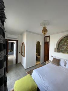 a bedroom with a white bed and a yellow chair at Dar Diaft'na in Marrakesh +69 photos