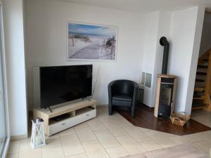 a living room with a flat screen tv and a chair at Ferienhaus Wellenreiter in Kappeln