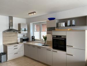 a kitchen with white cabinets and a black appliance at Ferienhaus Wellenreiter in Kappeln