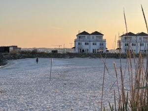 a person walking on the beach in front of two houses at Ferienhaus Wellenreiter in Kappeln