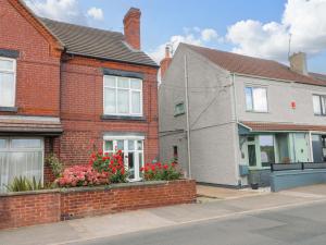 a brick house with flowers in front of it at Alfreton Cottage in Alfreton
