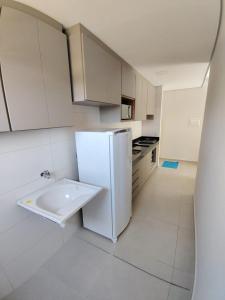 a kitchen with a white refrigerator and a sink at Apartamento Le Vert in Barretos