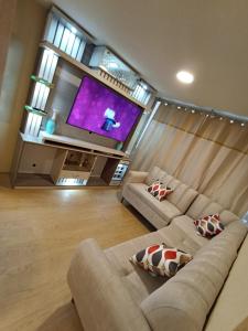a living room with two couches and a large screen tv at Departamento en estreno condominio la media central in Lima