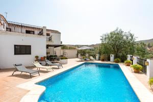 einen Pool mit zwei Stühlen neben einem Haus in der Unterkunft Casa rural Furones in Villanueva de Algaidas