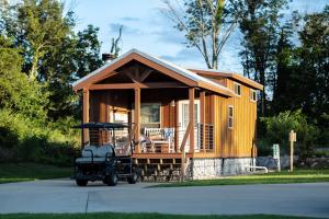 a tiny house with a car parked in front of it at Four Corners RV Resort in Antioch