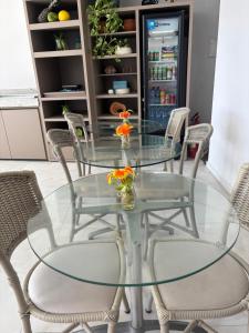 a glass dining room table with chairs and a refrigerator at Pousada Praia Pajuçara in Maceió