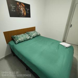 Un dormitorio con una cama con sábanas verdes y un póster. en Jockey of Itaparica 1, en Vila Velha