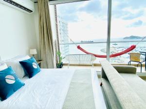 圣玛尔塔Blue Loft 14th floor with balcony overlooking the ocean and marina, Jacuzzi, Sauna, Turkish bath, swimming pool, gym, spa y bar的一间卧室，里面有一张床和一扇大窗户。