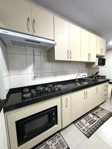 eine Küche mit weißen Schränken und einem Herd mit Backofen in der Unterkunft Davisis - Casa Ampla 2 Quartos e Garagem grande in Palmas