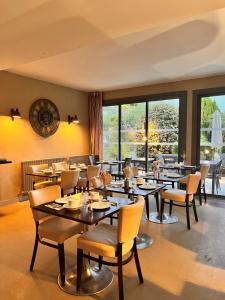 a dining room with tables and chairs and windows at Le Galet Hotel & Spa in Saint-Philibert
