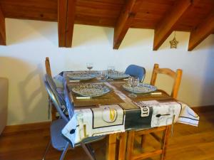 a wooden table with chairs and plates and glasses on it at Le Nid Mansardé in Ustou