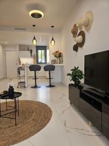 a living room with a flat screen tv and chairs at Casita Feliz in San Pedro del Pinatar