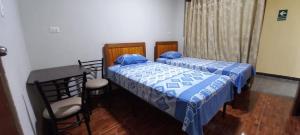 a bedroom with two beds and a table and chairs at Hospedaje Miramar in Máncora