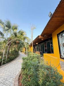 a sidewalk next to a yellow building with palm trees at Đầm sen Resort in Hòa Lạc