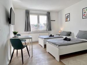 a bedroom with two beds and a desk and a table at Work Inn Rhein Ruhr Appartement in Duisburg