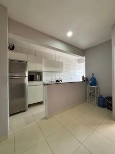 une cuisine avec des armoires blanches et un réfrigérateur en acier inoxydable dans l'établissement Apartamento para romeiros- próximo ao santuário de aparecida, à Roseira